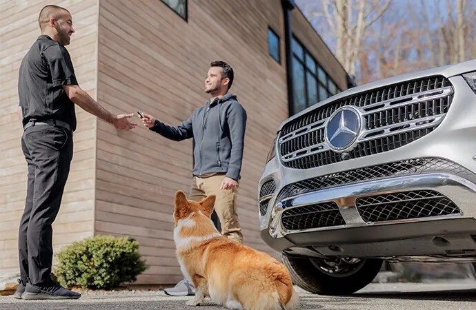 Mercedes-Benz technician picking up an SUV from a man with a dog