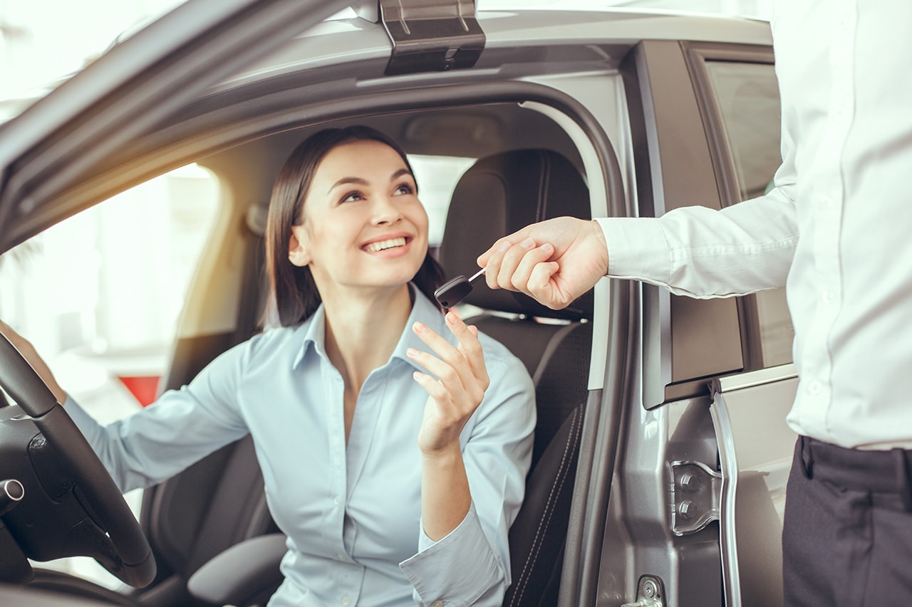 Woman accepting a key from a car dealer before a test drive