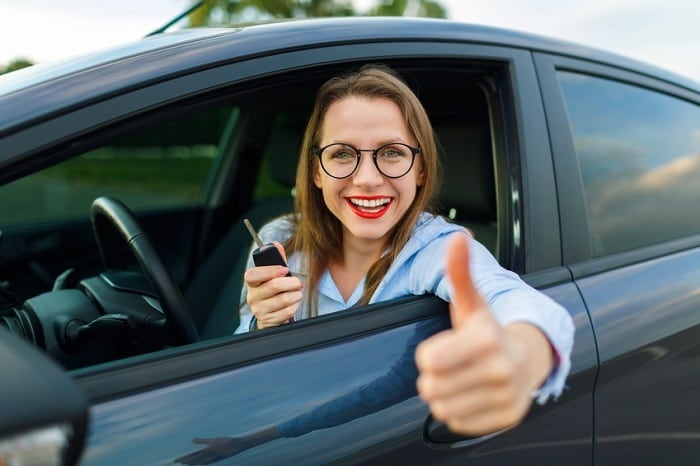 Happy woman in a car giving a thumbs up