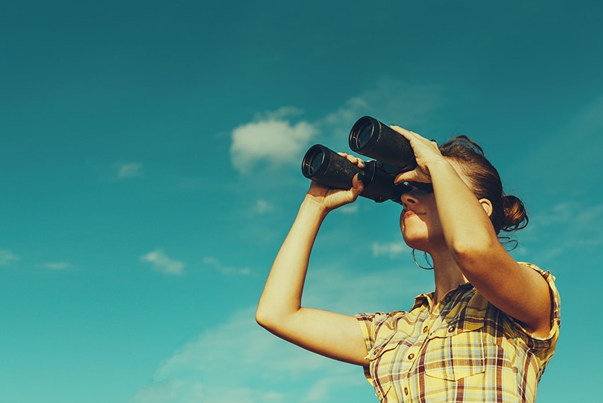 woman looking at the sky through binoculars