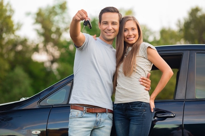 Couple standingin front of their new car image