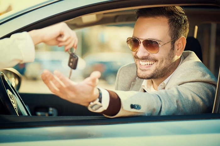 Cool dude in shades accepting the key to his new used car