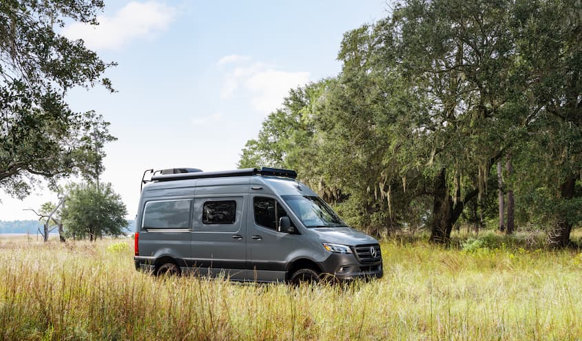 Section 179 - Van Line.jpg A Mercedes-Benz van parked in a grassy field surrounded by trees.