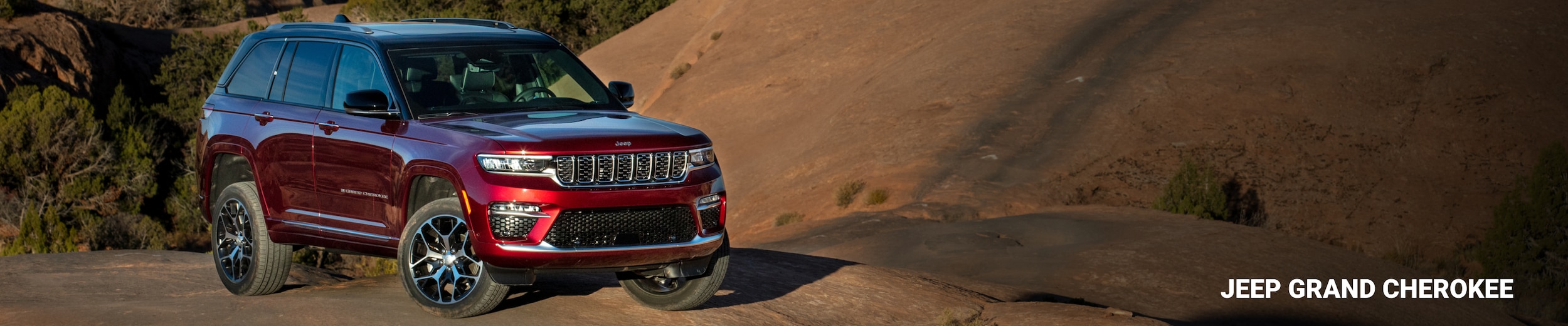 2025 Jeep Grand Cherokee Summit Reserve in Velvet Red Pearl photographed outdoors on off-road terrain