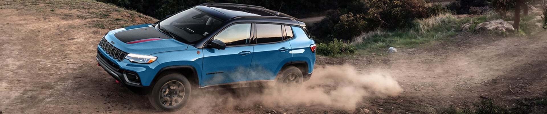 2025 Jeep Compass Trailhawk 4x4 shown in Hydro Blue Pearl-Coat off-roading on mountainous terrain