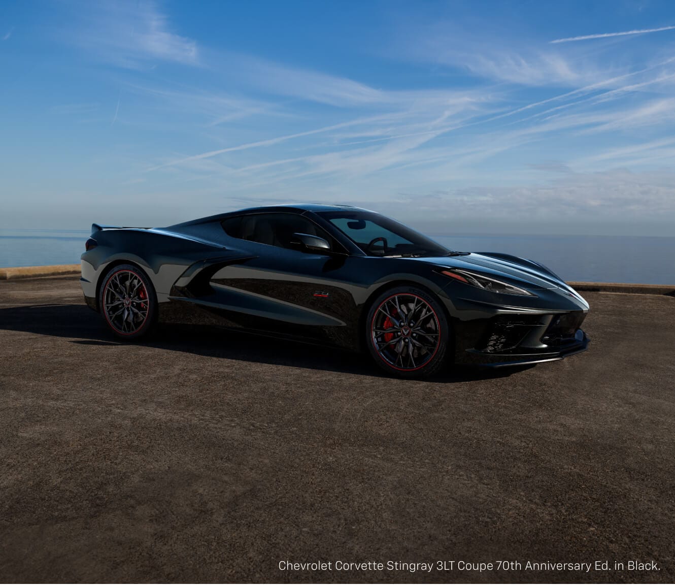Front quarter view of a Chevrolet Corvette Stingray 70th Anniversary Edition in Carbon Flash Metallic by an ocean.