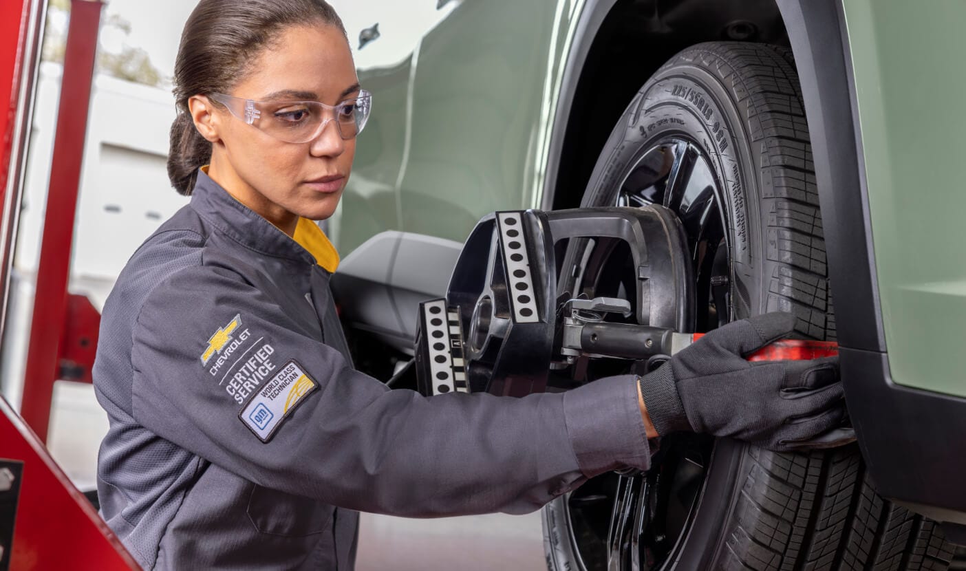 Chevy Service Technician replacing tires on a green Chevrolet