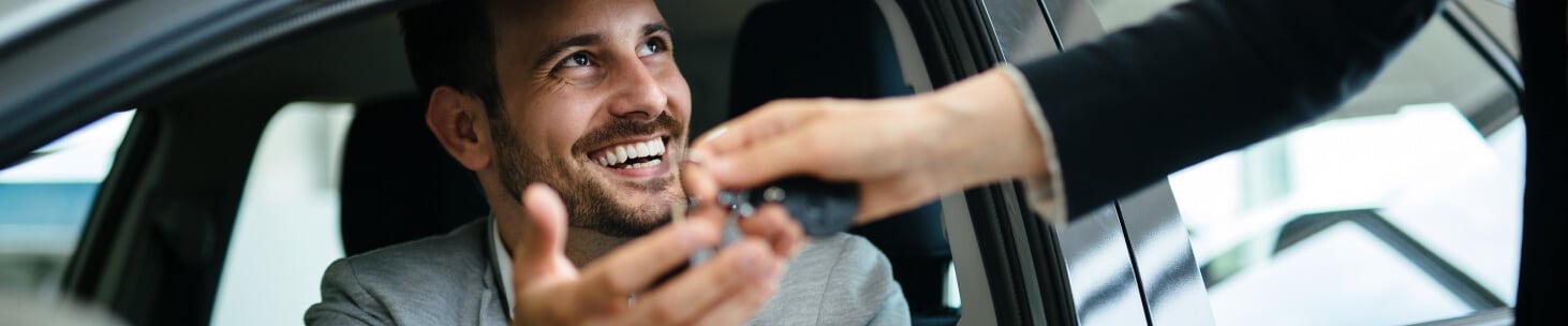 A man in the driver's seat of a new car being handed keys to his new Chevrolet