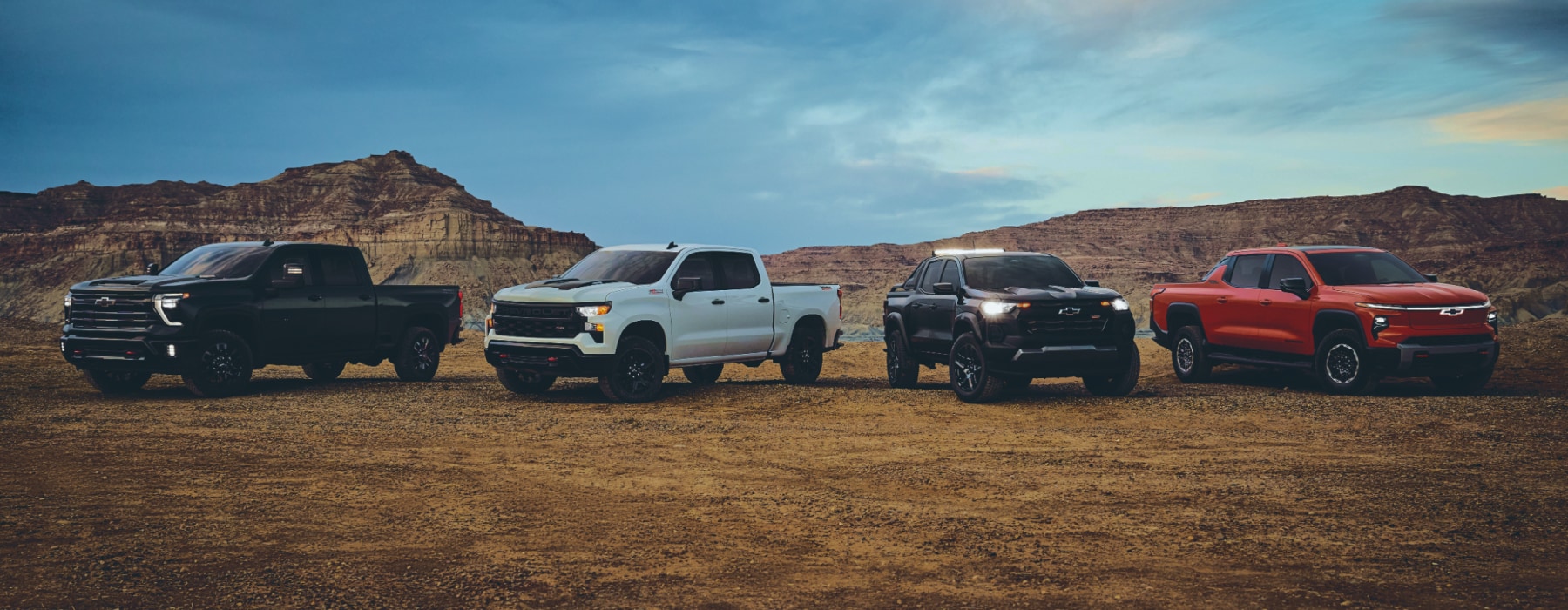 Four Chevy Trucks: Silverado EV, Silverado 1500, Colorado, and Silverado 2500 parked on dirt