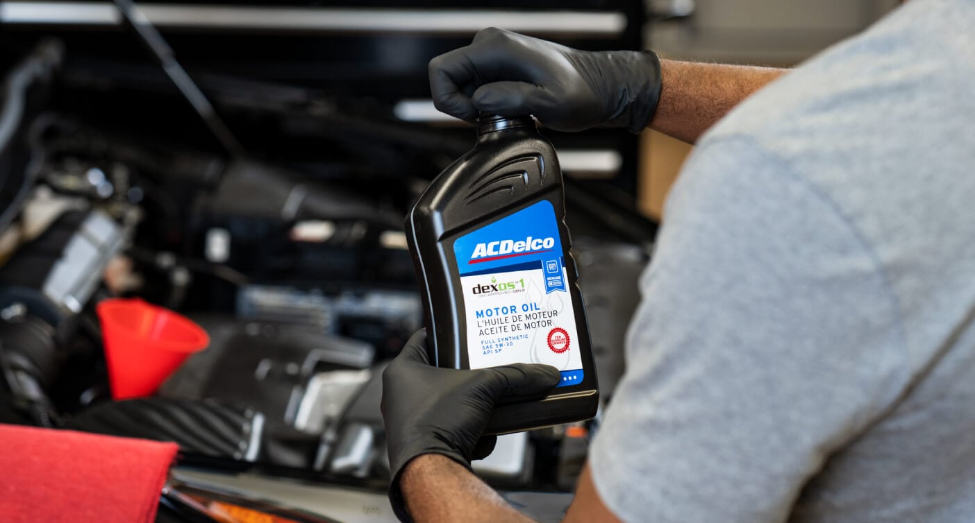 Chevy Service Technician filling the oil of a new Chevrolet