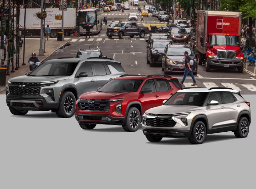 Front three-quarter view comparison of a 2026 Chevrolet Traverse Z71 in Sterling Gray, a 2026 Chevrolet Equinox RS in Radiant Red Tintcoat and a 2026 2026 Chevrolet Trailblazer ACTIV in White Sands against a city street.