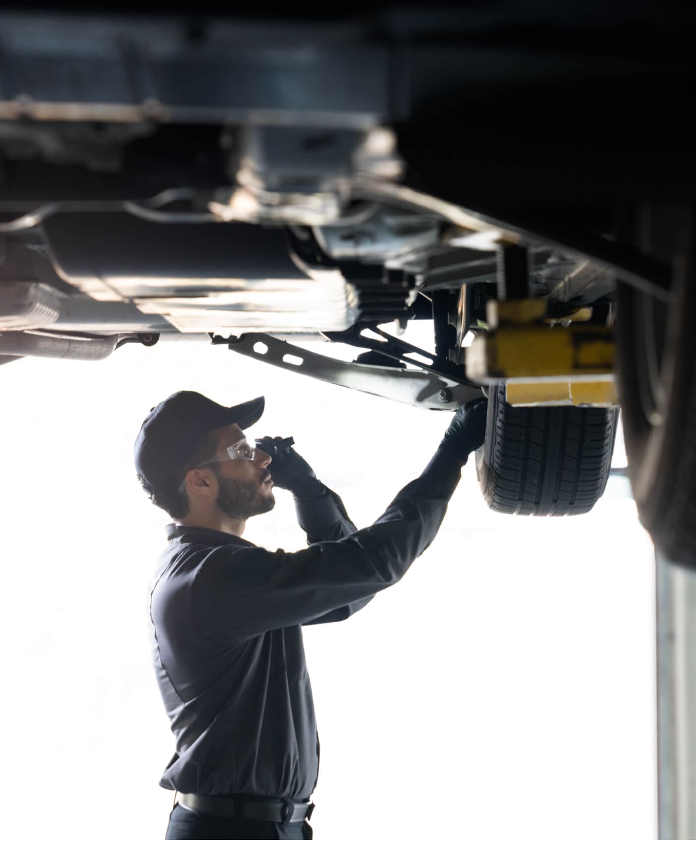 Chevrolet Mechanic performing a multi-point vehicle inspection with a Chevy up on a garage lift