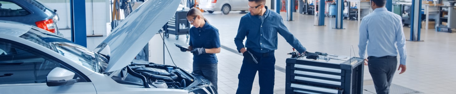 Mechanics servicing a chevy vehicle inside of a dealership Chevrolet service garage