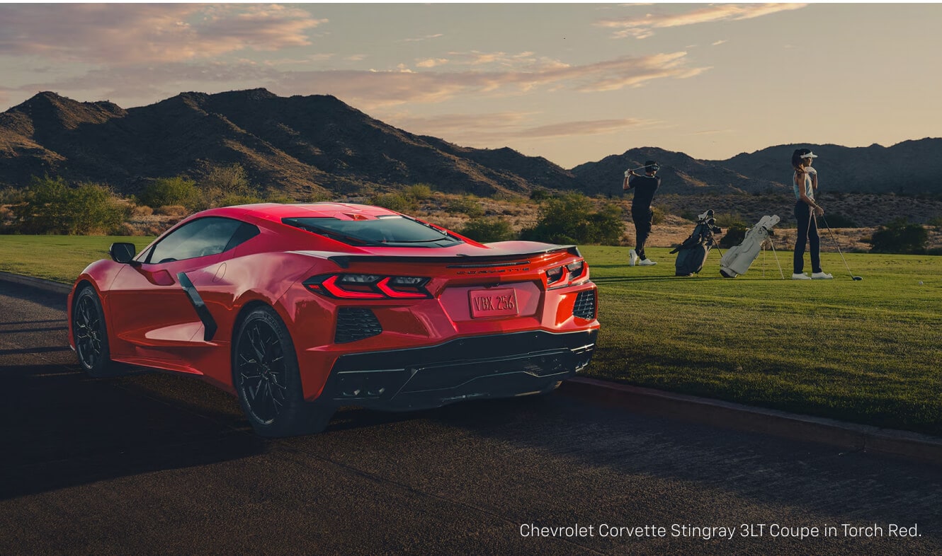 Back view of a Chevrolet Corvette Stingray in Torch Red showing its dual tail lights at a golf course.
