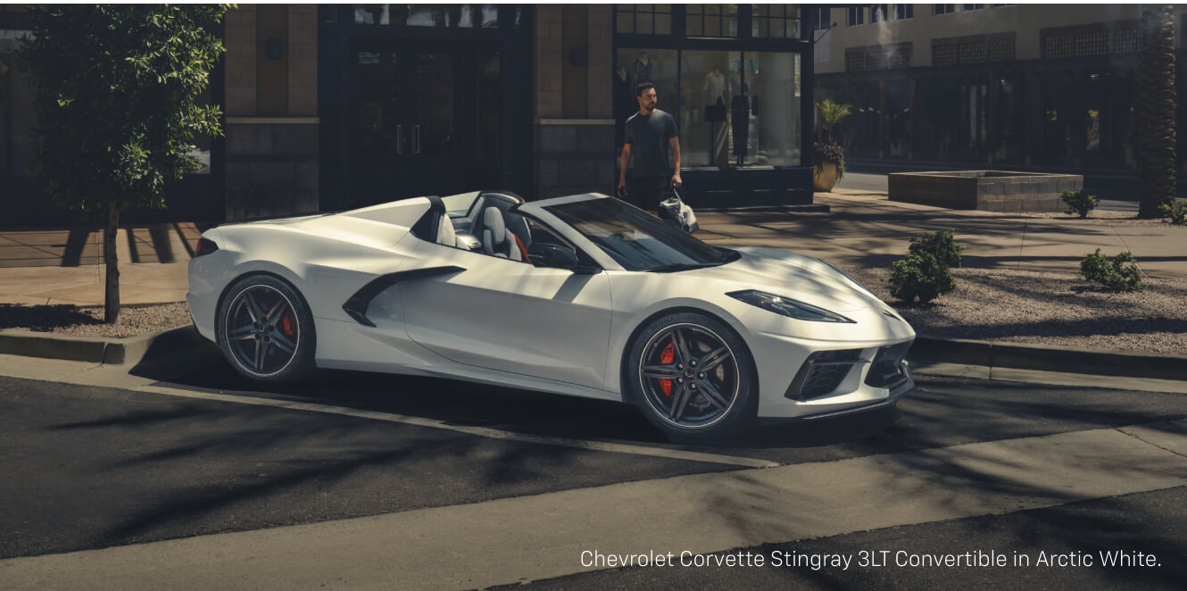 Front quarter view of a Chevrolet Corvette Stingray Convertible in Arctic White parked on a city street.
