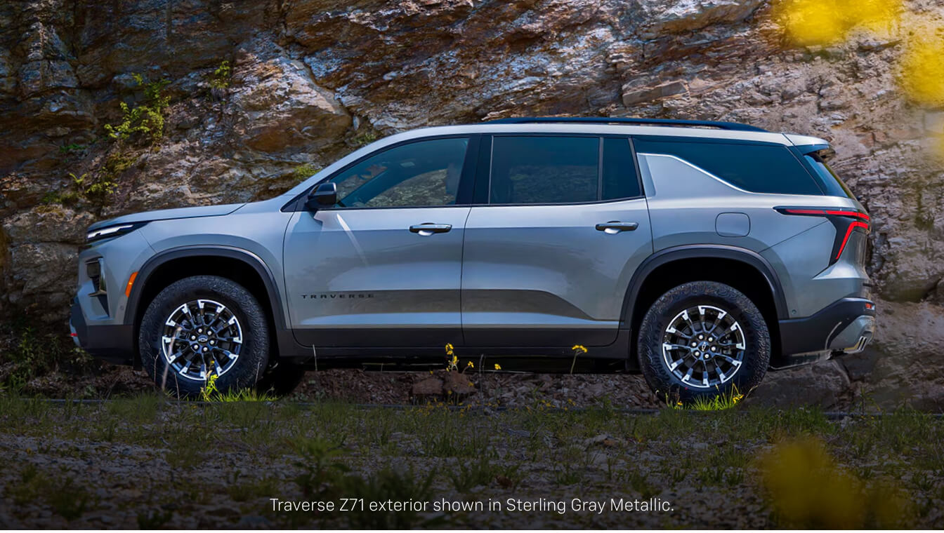 Side profile view of a gray Chevrolet Traverse Z71 showcasing its off-road wheels against a rocky cliff.