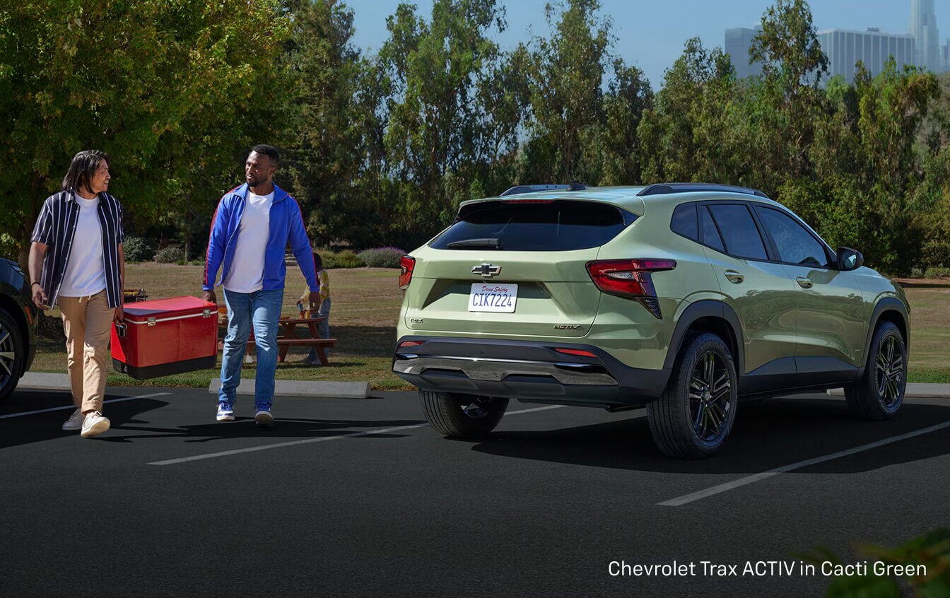 Two men carrying a red cooler to their 2026 Chevy Trax ACTIV in Cacti Green