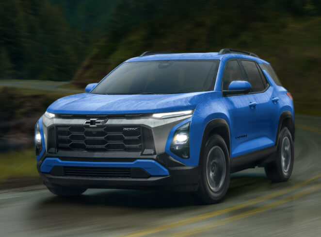 Front exterior action shot of a blue 2027 Equinox driving on a rainy forest highway.
