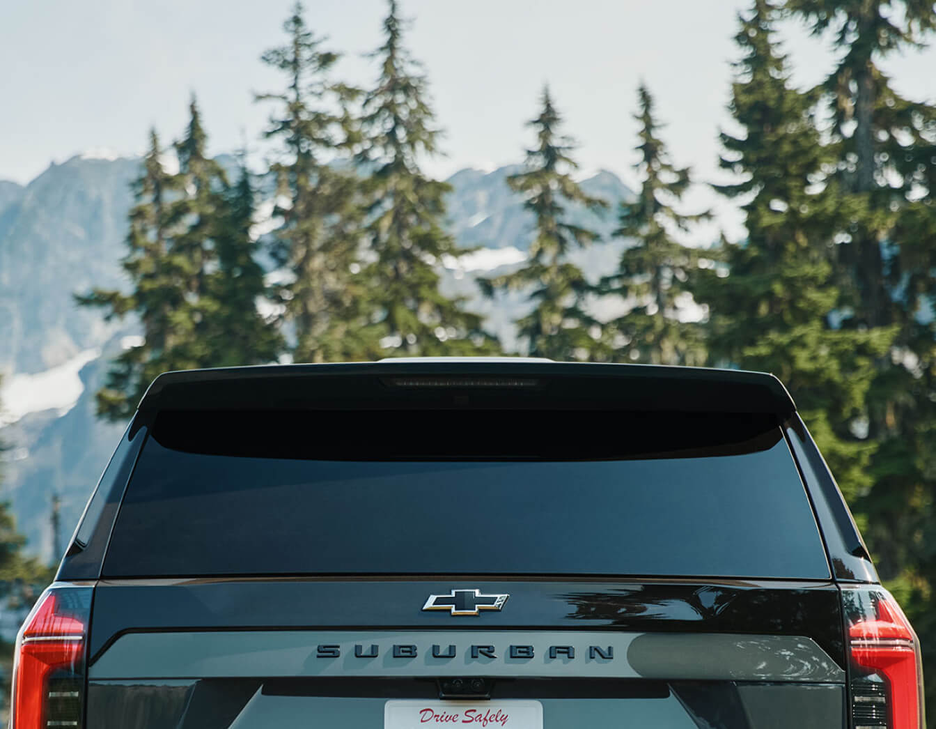 Split view of a green 2026 Chevy Suburban Z71: rear, front, and close-up badge views with mountain backdrops.
