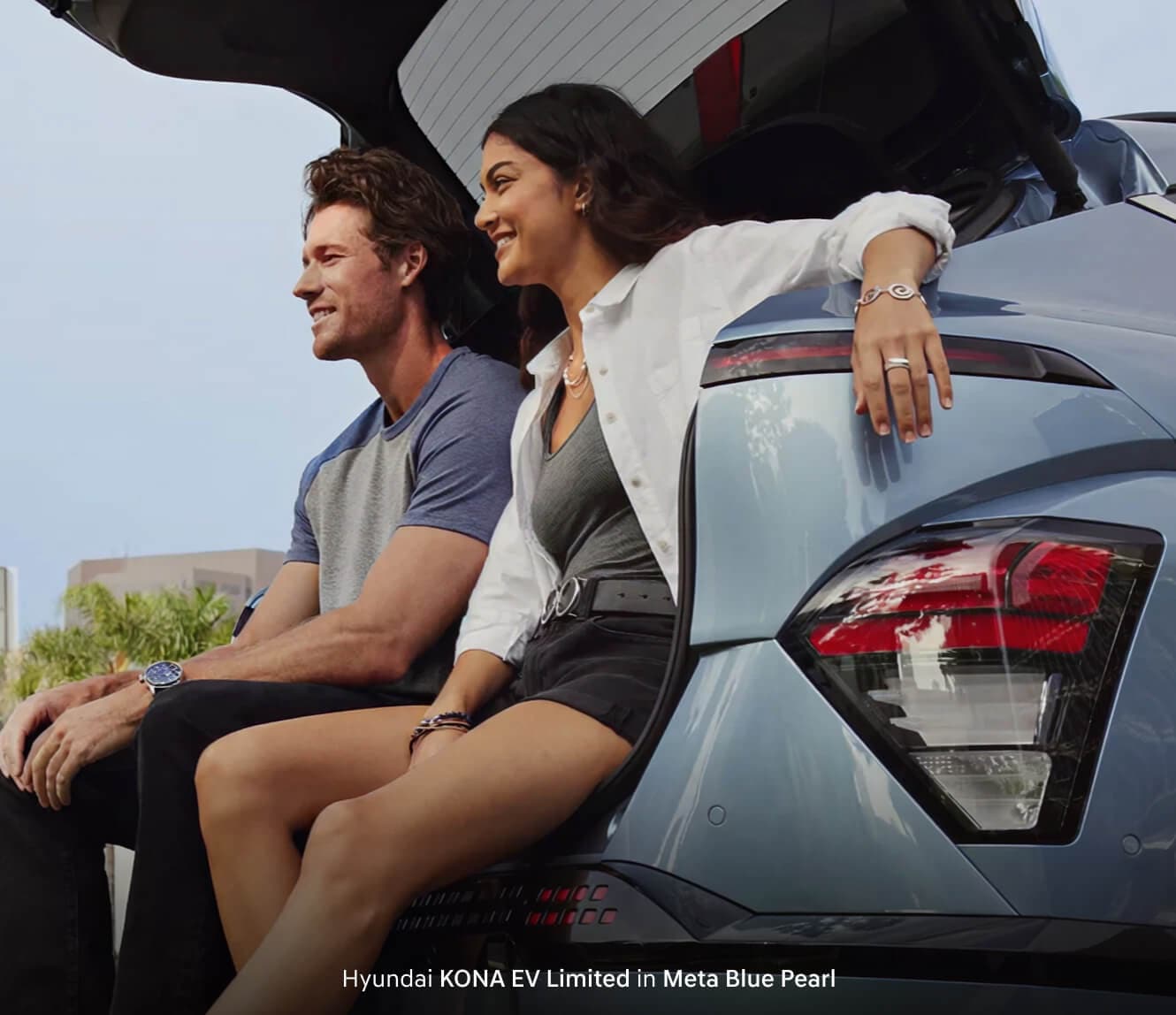 Couple lounging in the trunk of their Meta Blue Pearl Hyundai Kona EV Limited