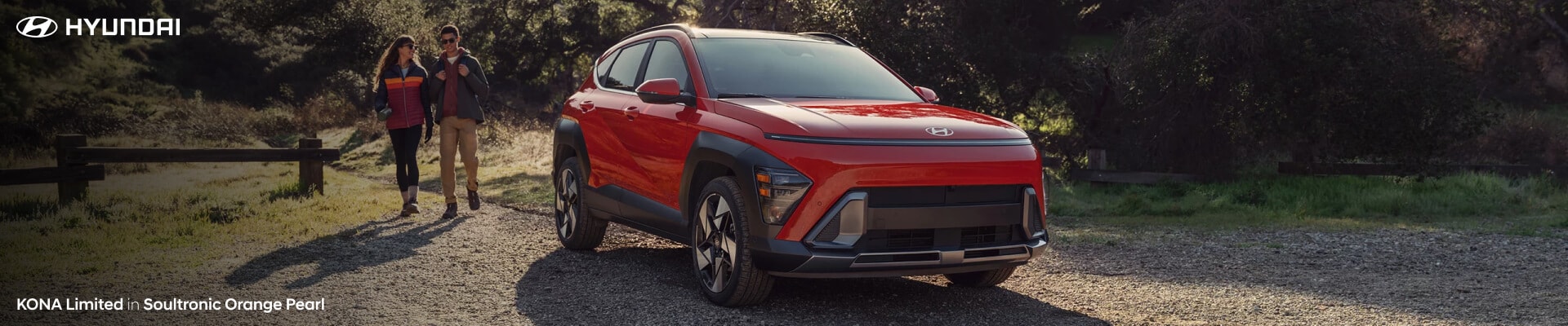 A new Hyundai Kona Limited in Soultronic Orange Pearl parked on a dirt road