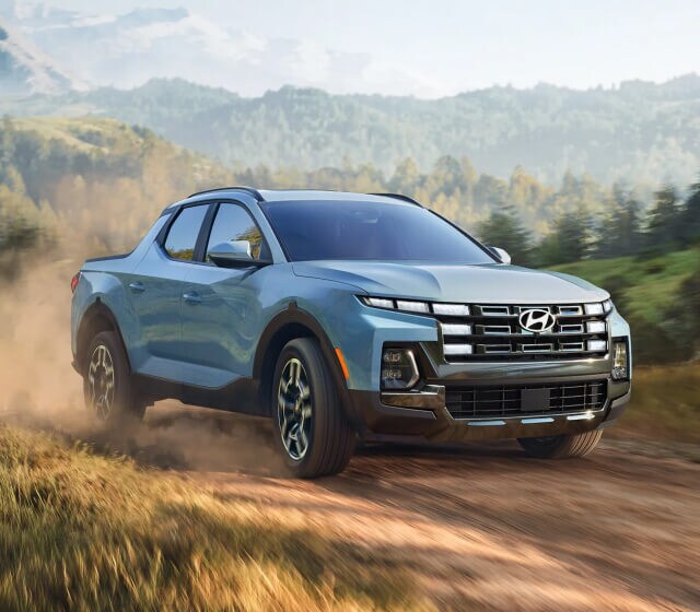 Front quarter view of a Hyundai Santa Cruz Limited in Blue throwing up dirt while accelerating
