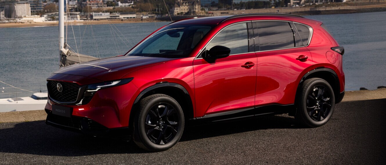 Red 2026 Mazda CX-5 parked in front of a boat and water