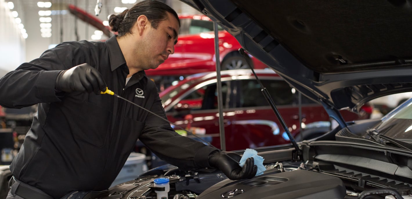 Mazda service technician performing an oil change on a Mazda