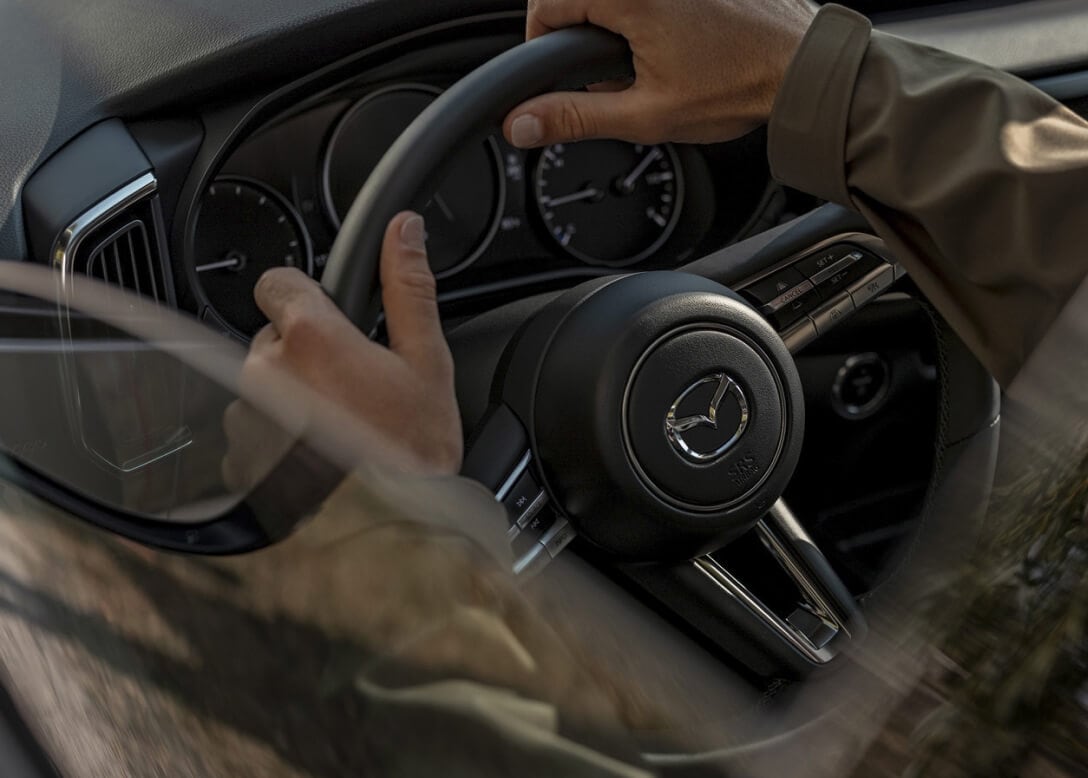 Close-up of a man holding the steering wheel of a Mazda CX-50 Hybrid