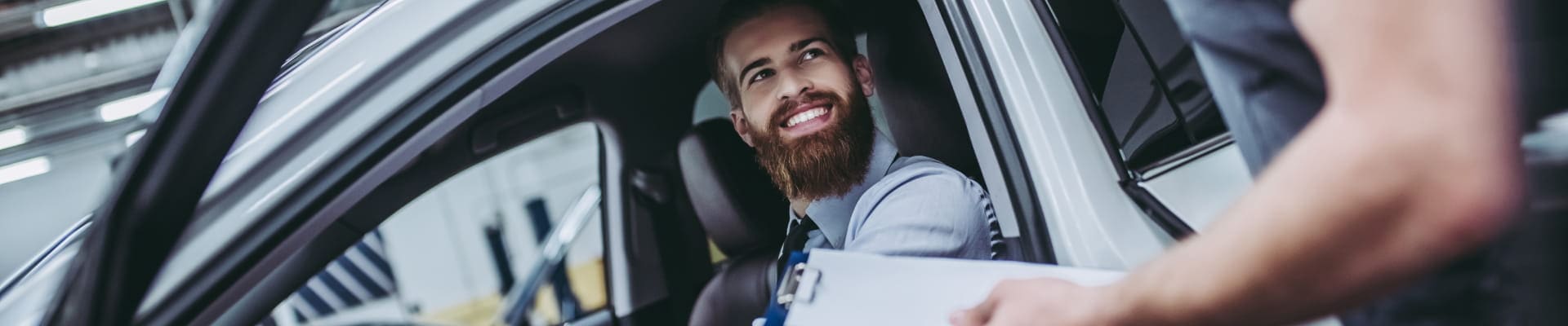 Customer speaking with an automotive technician while seated inside a vehicle.