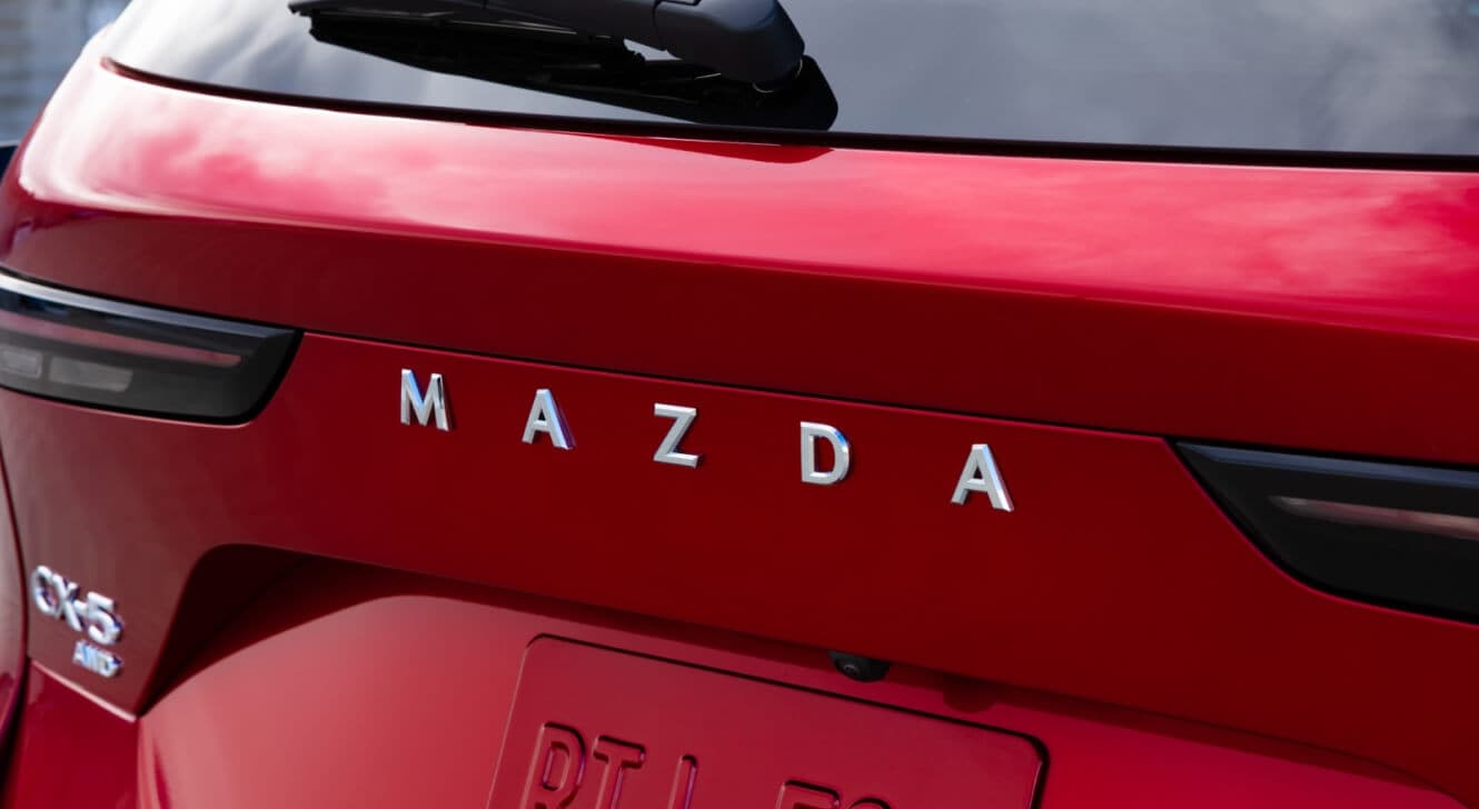 Close-up on the Mazda insignia on the tailgate of a red 2026 Mazda CX-5
