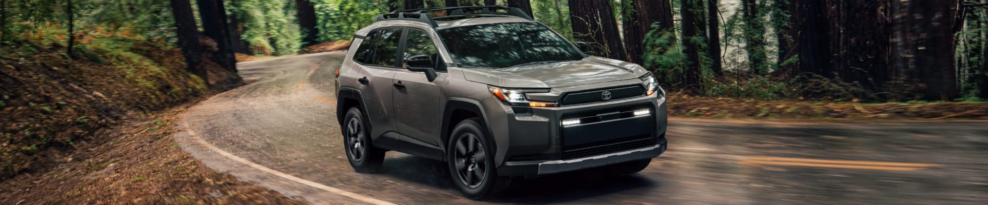 2026 Toyota RAV4 Woodland shown in Urban Rock driving through a forest