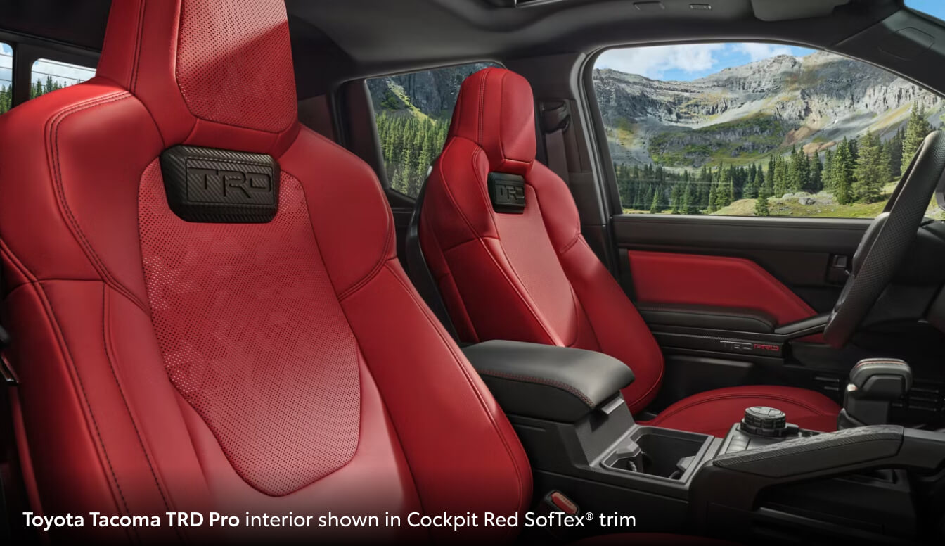 Interior front seat view of a 2026 Toyota Tacoma featuring Cockpit Red SoftTex trim