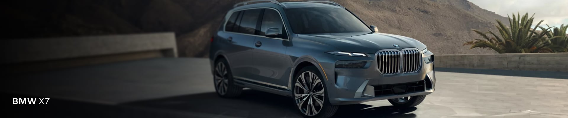 A new 2026 BMW X7 parked in front of a sunlit mountain