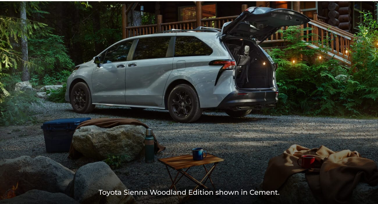 2026 Cement Toyota Sienna Woodland Edition with an open rear hatch parked at a forest campsite.