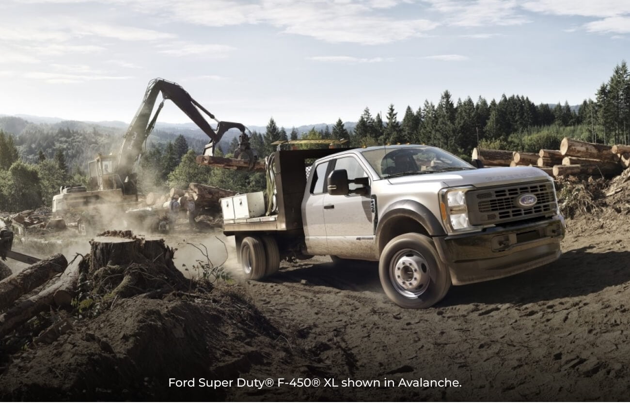 2026 Avalanche Ford Super Duty F-450 XL on a dirt logging site as an excavator moves logs.