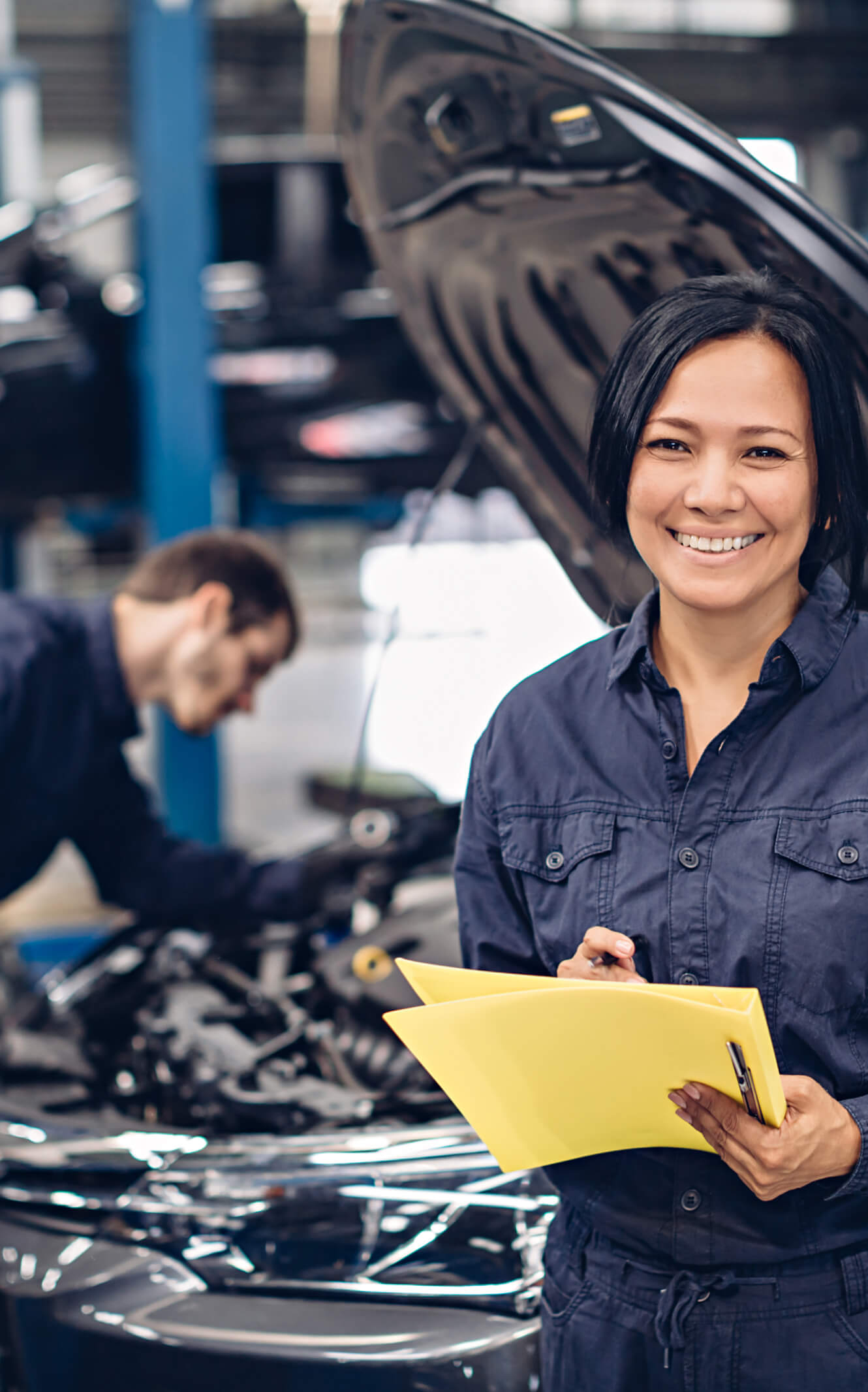 Two McGee auto service technicians working on a vehicle inside of McGee's full-service service center
