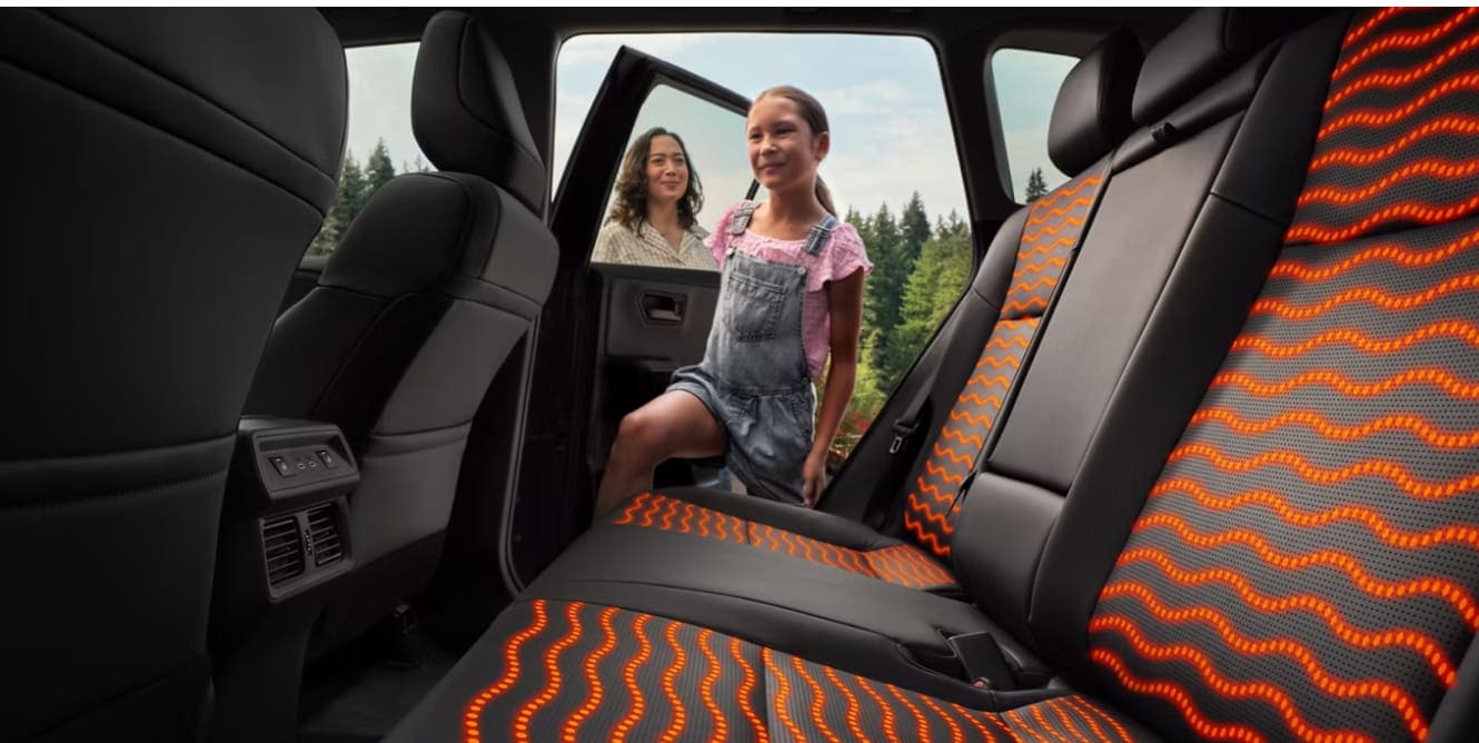 Interior backseat shot of a girl entering a 2026 Toyota RAV4 Limited with black and red interior