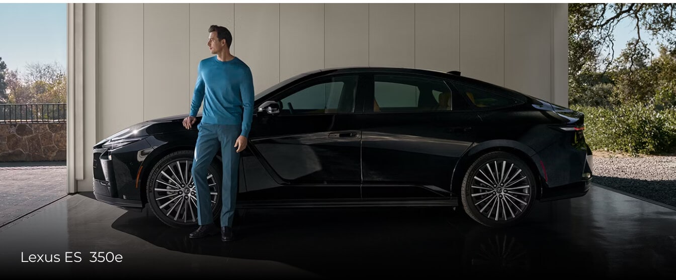 Side view of a man leaning on a black Lexus ES 350e while parked in an upscale carport.