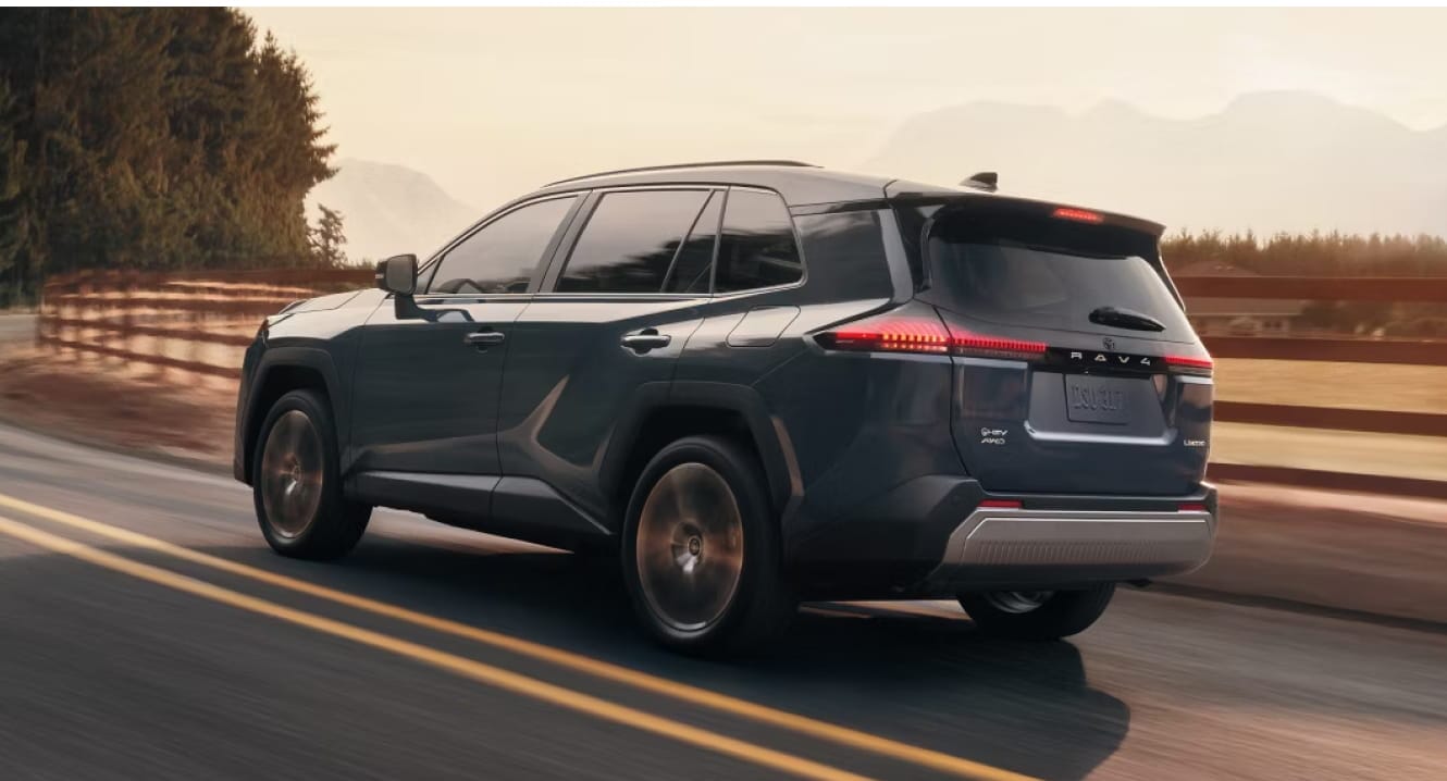 2026 Toyota RAV4 Limited shown in Storm Cloud driving by a ranch