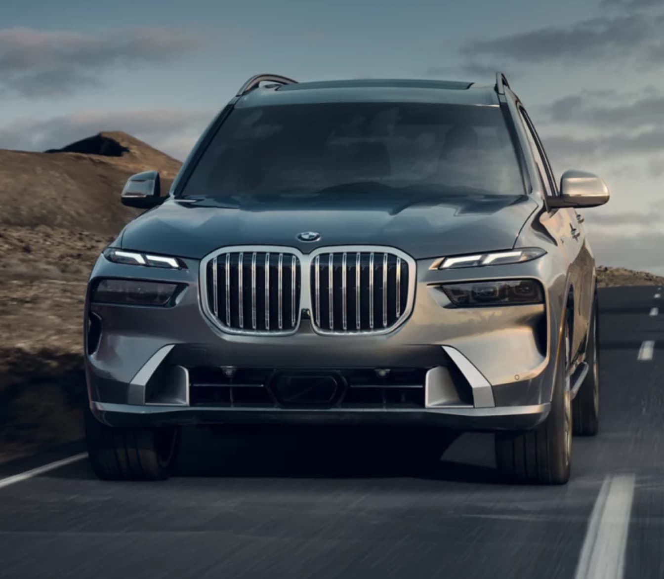 Front view of a new 2026 BMW X7 driving on an empty road