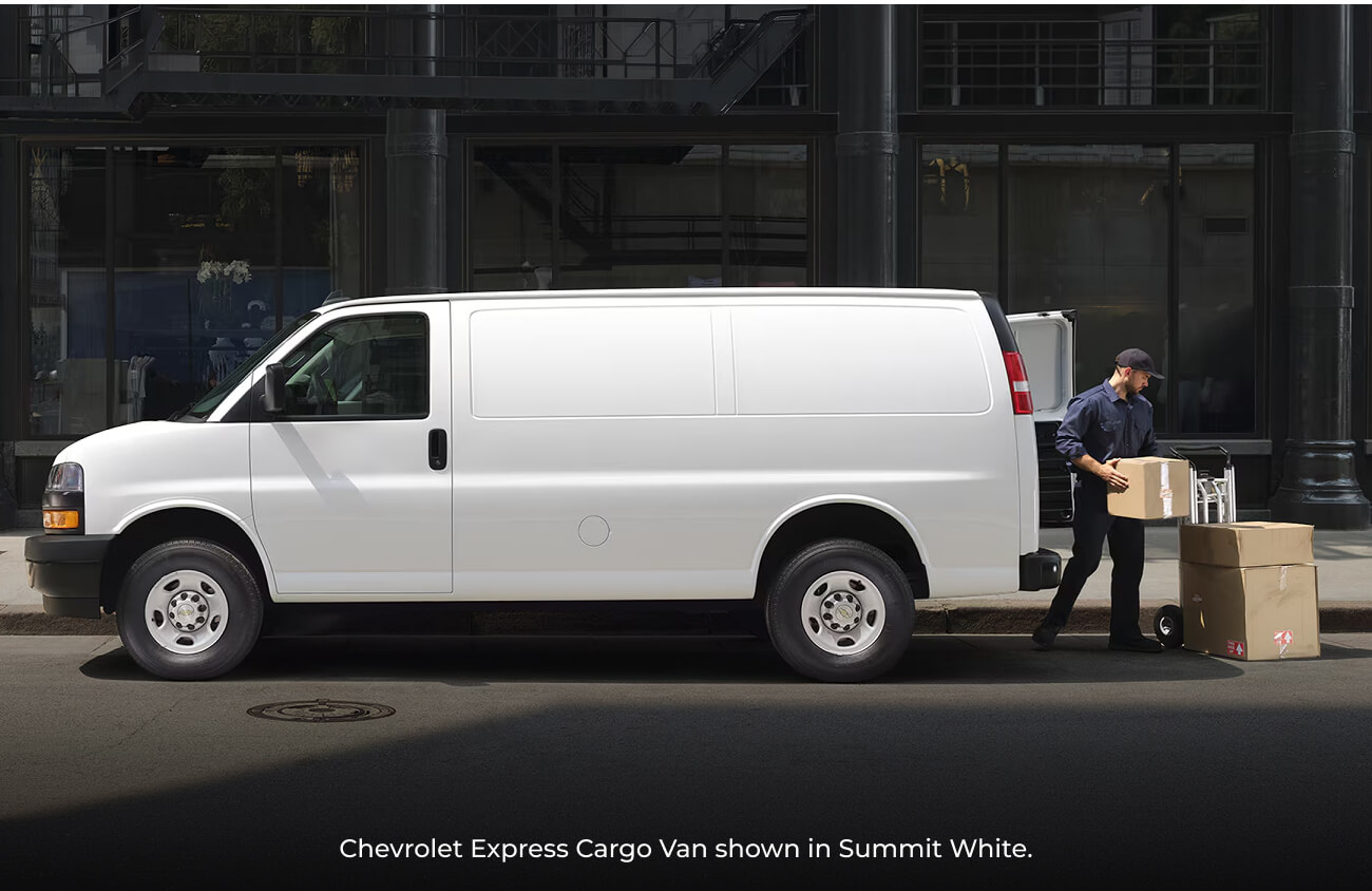 2026 Summit White Chevrolet Express Cargo Van parked on a city street as a delivery worker unloads cardboard boxes.