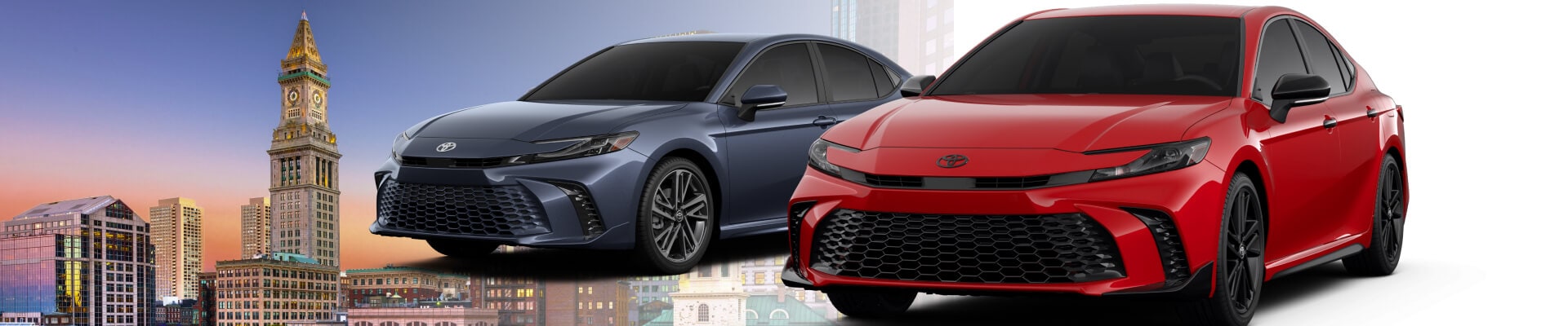 A 2026 Toyota Camry XSE Hybrid in Dark Cosmos and a 2026 Toyota Camry Nightshade in Supersonic Red superimposed in front of the Boston skyline