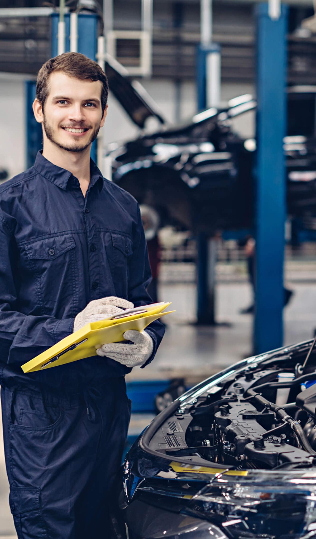 McGee Automotive Service Technician making notes in front of the engine of a car