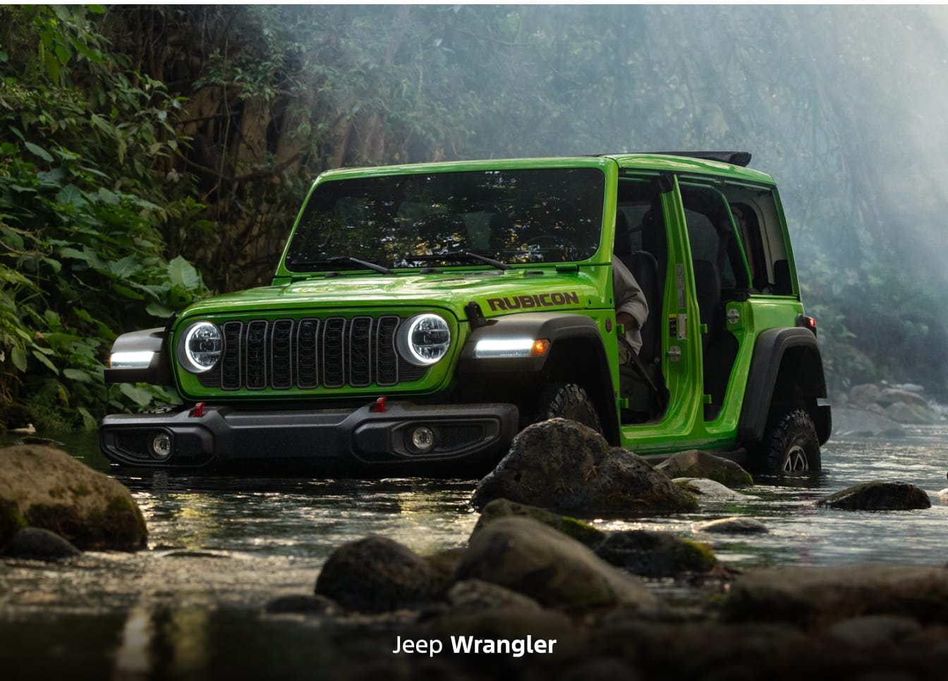A green 2026 Jeep Wrangler Rubicon driving through a creek