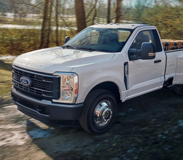 New Ford F-350 in Oxford White driving through woodland terrain