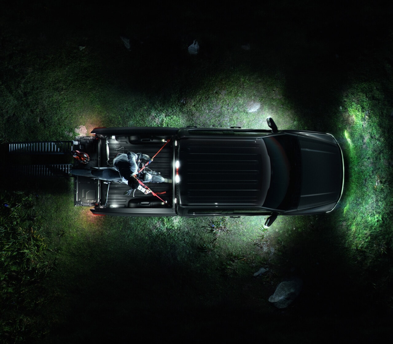 Birdseye view of a F-150 Lightning Lariat with front, side, and rear lights on in the dark