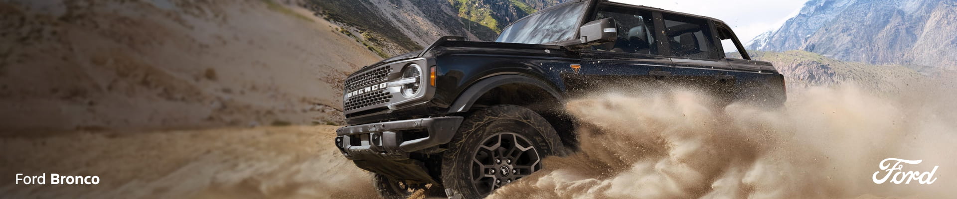 2026 Ford Bronco Badlands in black kicking up sand in front of a mountainous backdrop