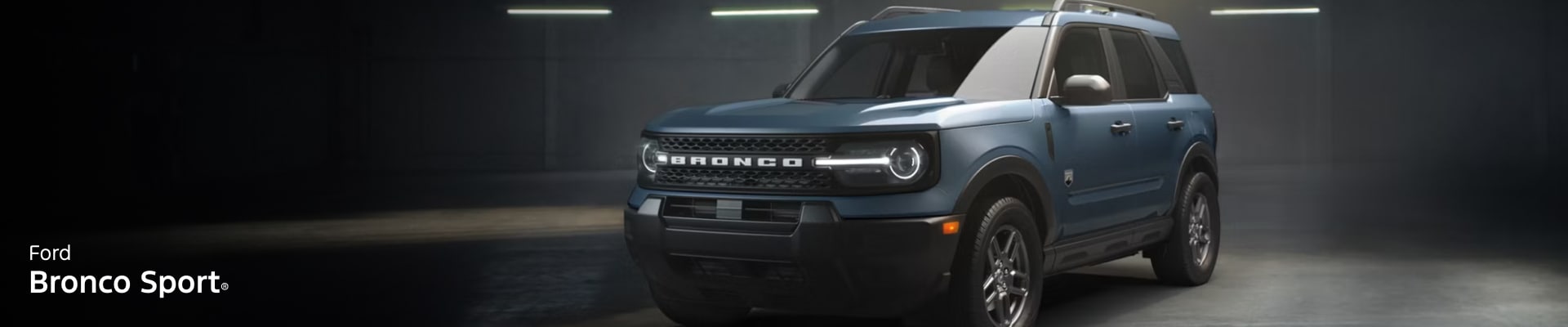 A sleek 2026 Ford Bronco Sport stands in a dimly lit garage, exuding a rugged yet modern vibe. The headlights are on, highlighting its bold grille design.