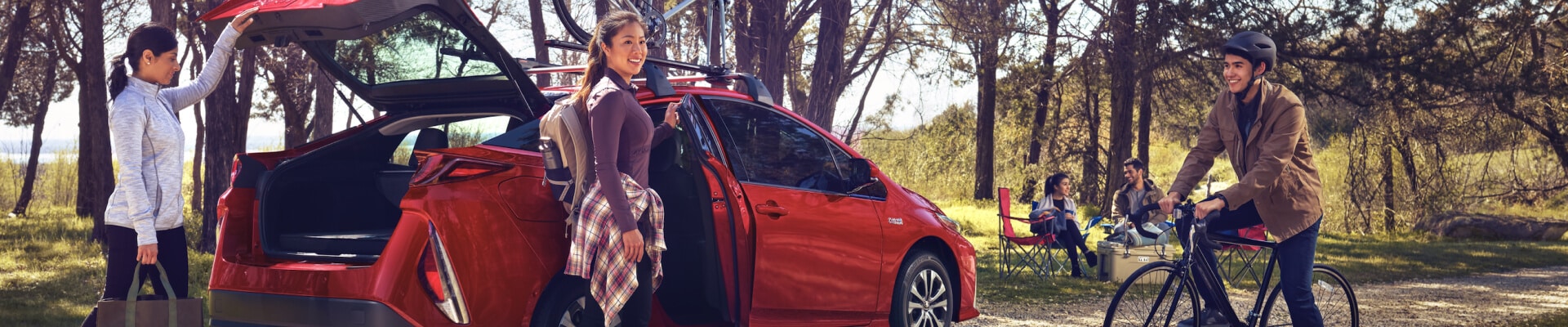 Two women getting into a red Toyota Prius at a park